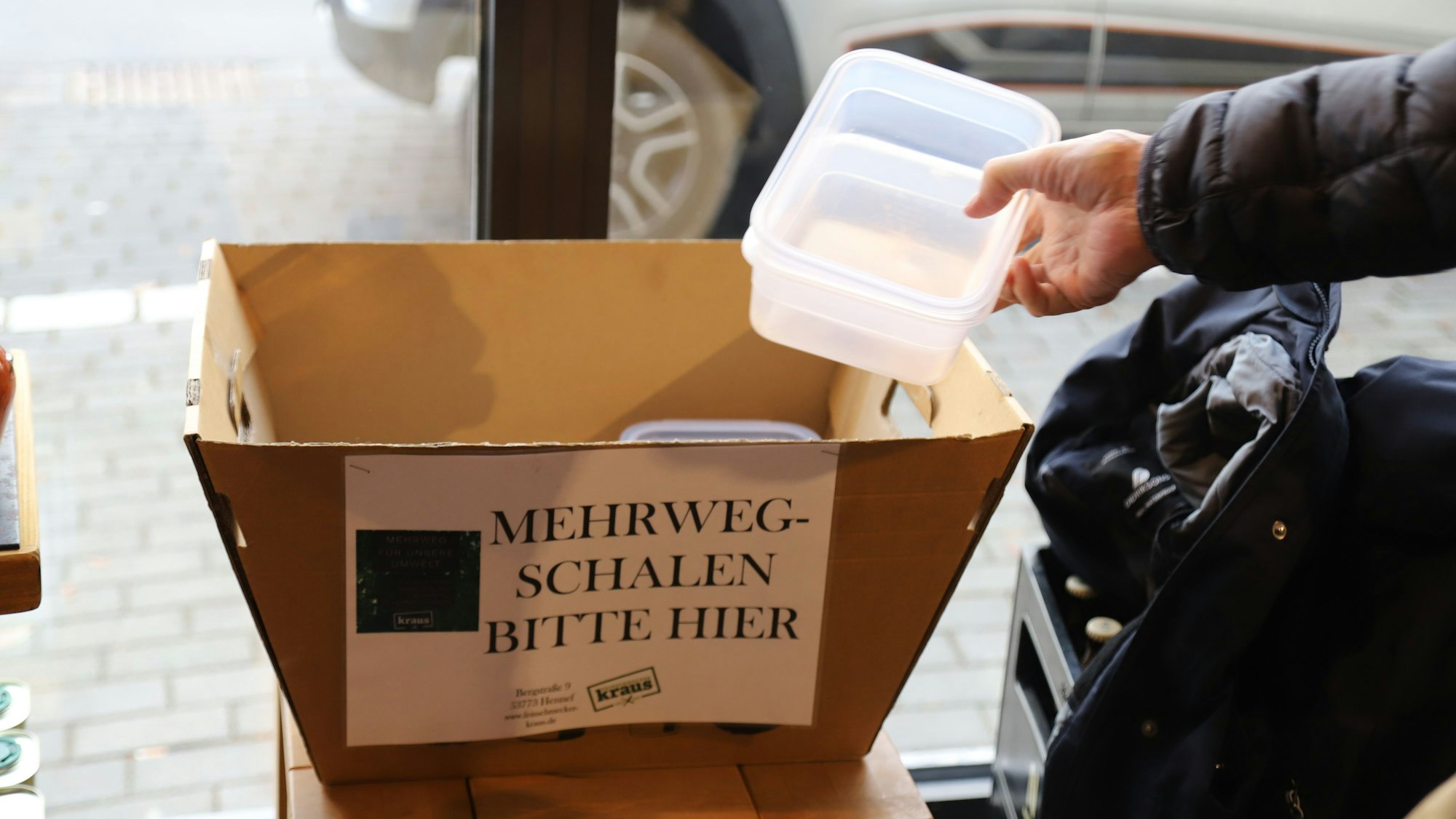 Ein Mann legt eine Kunststoffschale in einen Pappkarton.