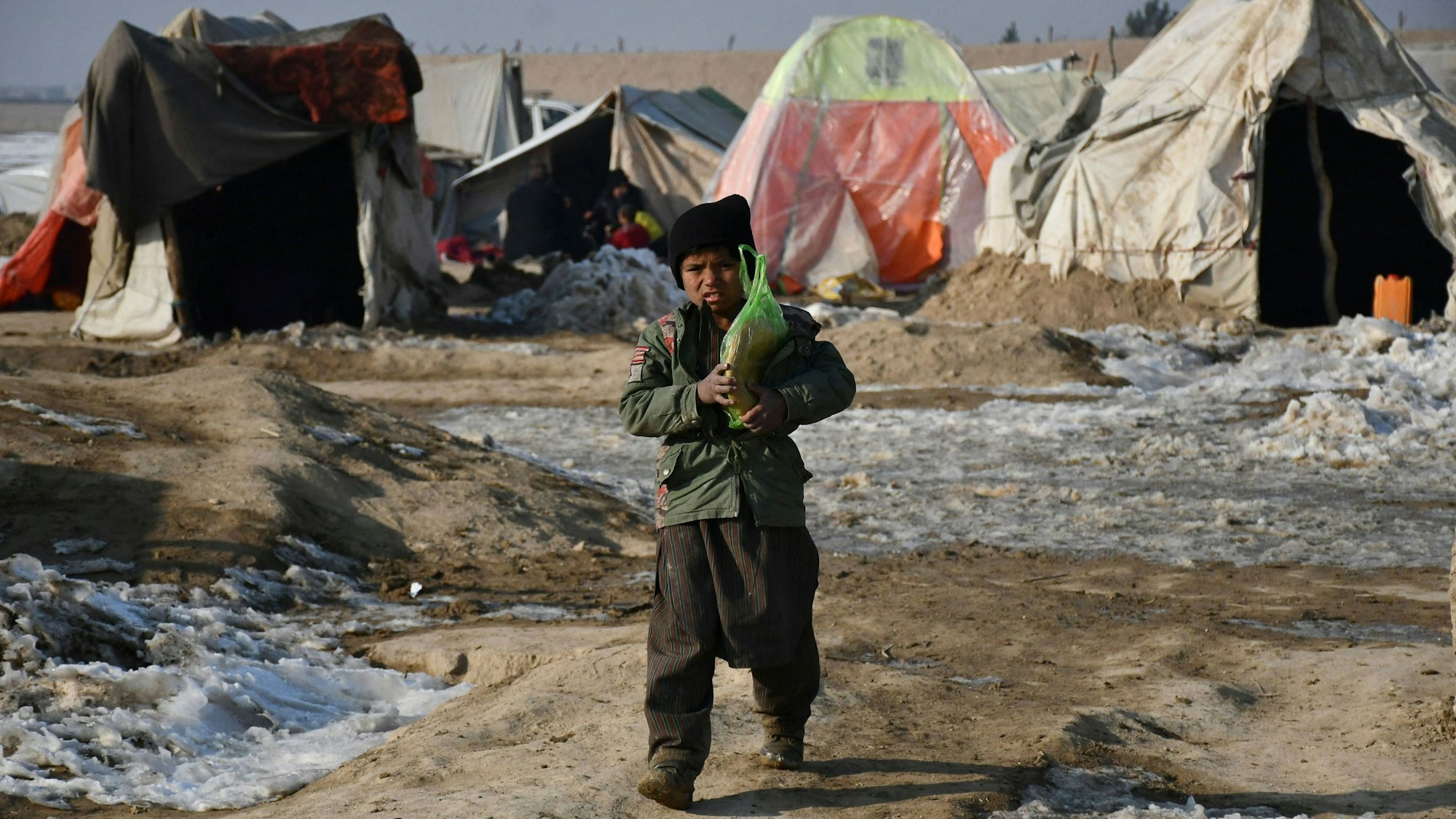 Ein Junge läuft durch eine zugefrorene Landschaft, im Hintergrund sind Zelte aufgestellt