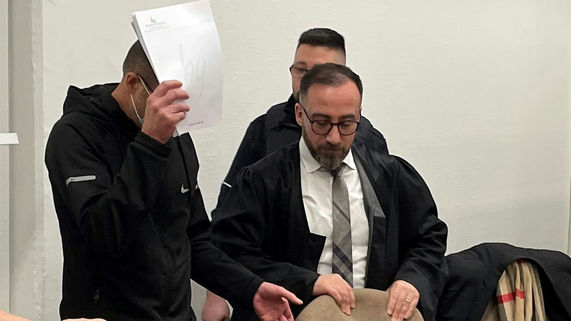 Der Angeklagte (l.) mit seinem Verteidiger und einem Wachtmeister beim Auftakt des Mordprozesses am Landgericht Köln.