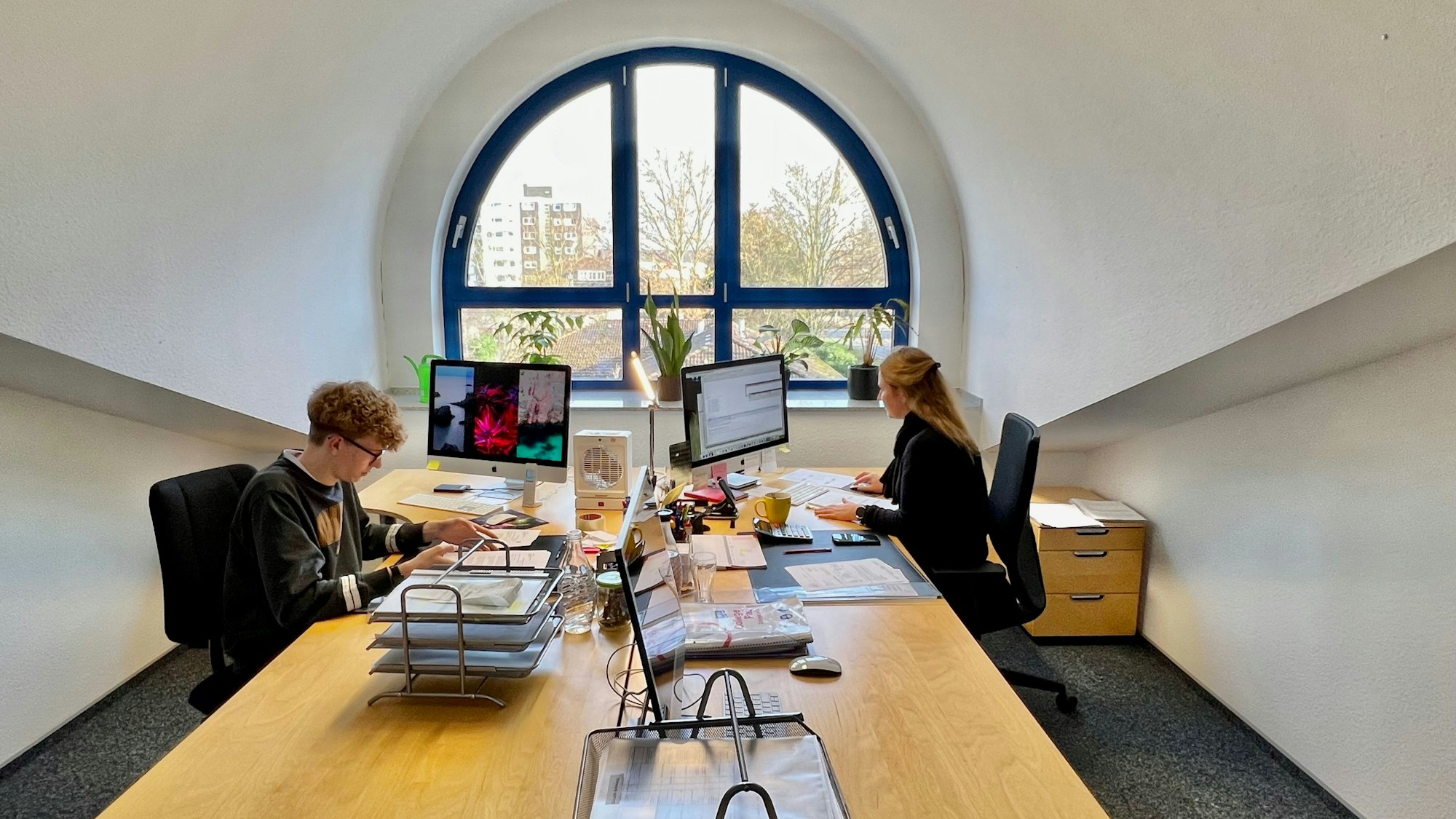 Zwei Mitarbeitende im Büro von Noldens Eventagentur an ihren Schreibtischen