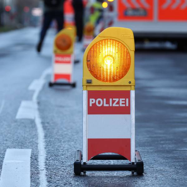 Eine Warnbarke mit der Aufschrift „Polizei“ steht vor einem Rettungswagen an einer abgesperrten Unfallstelle. (Symbolbild)