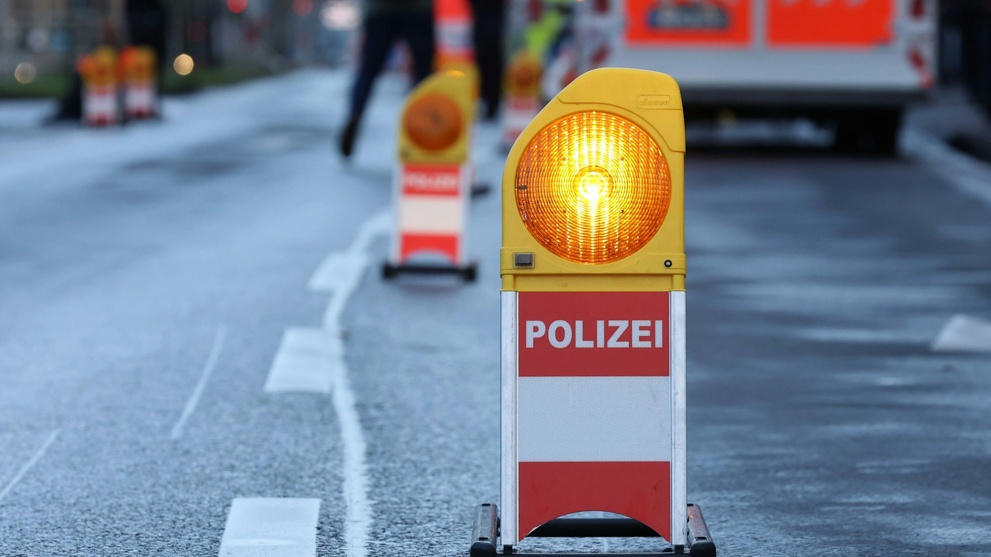 Eine Polizei-Warnbake steht auf einer Straße in Köln.