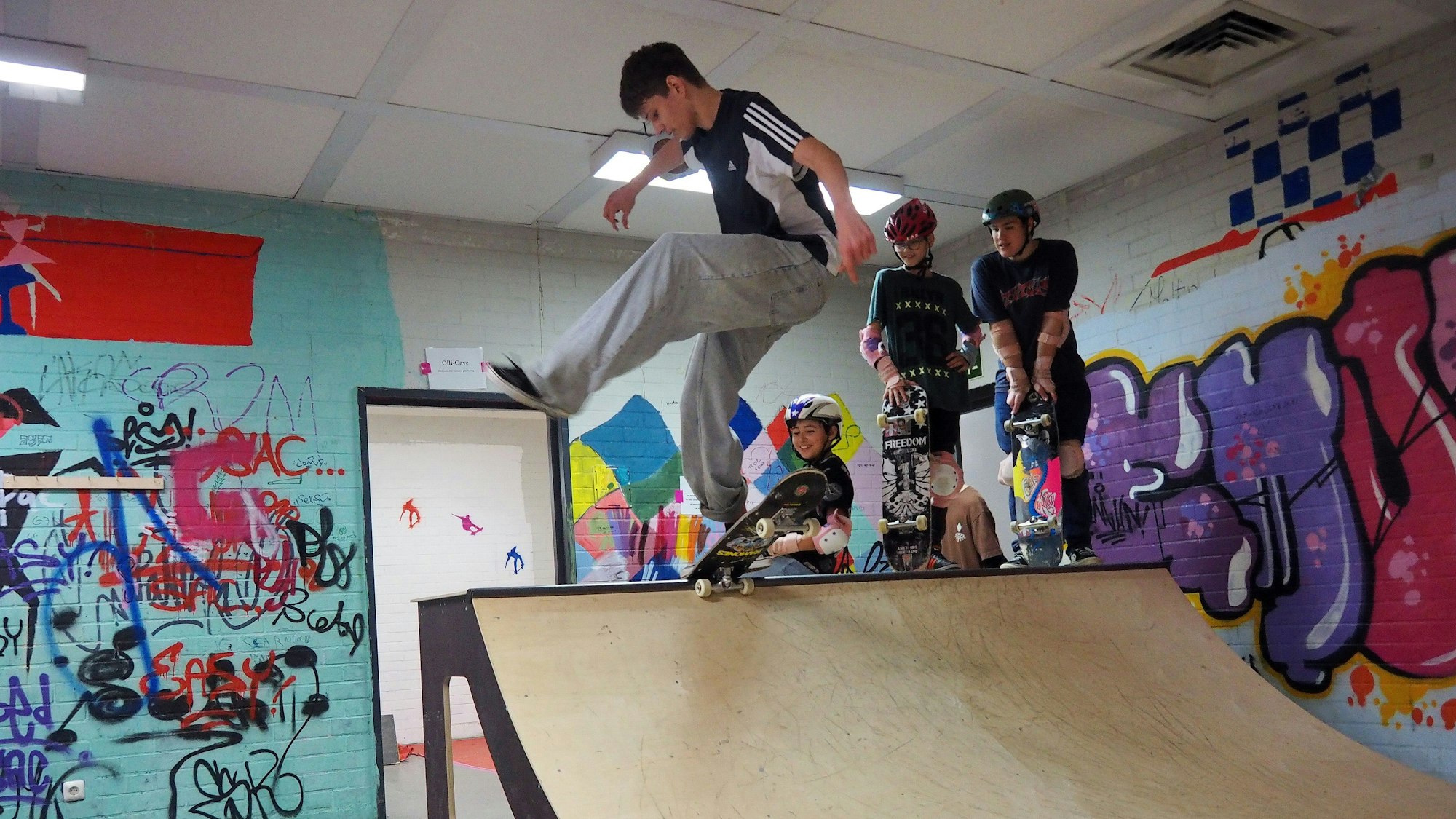 Schüler, der vor drei anderen Schülern einen Trick auf der Skaterrampe vorführt