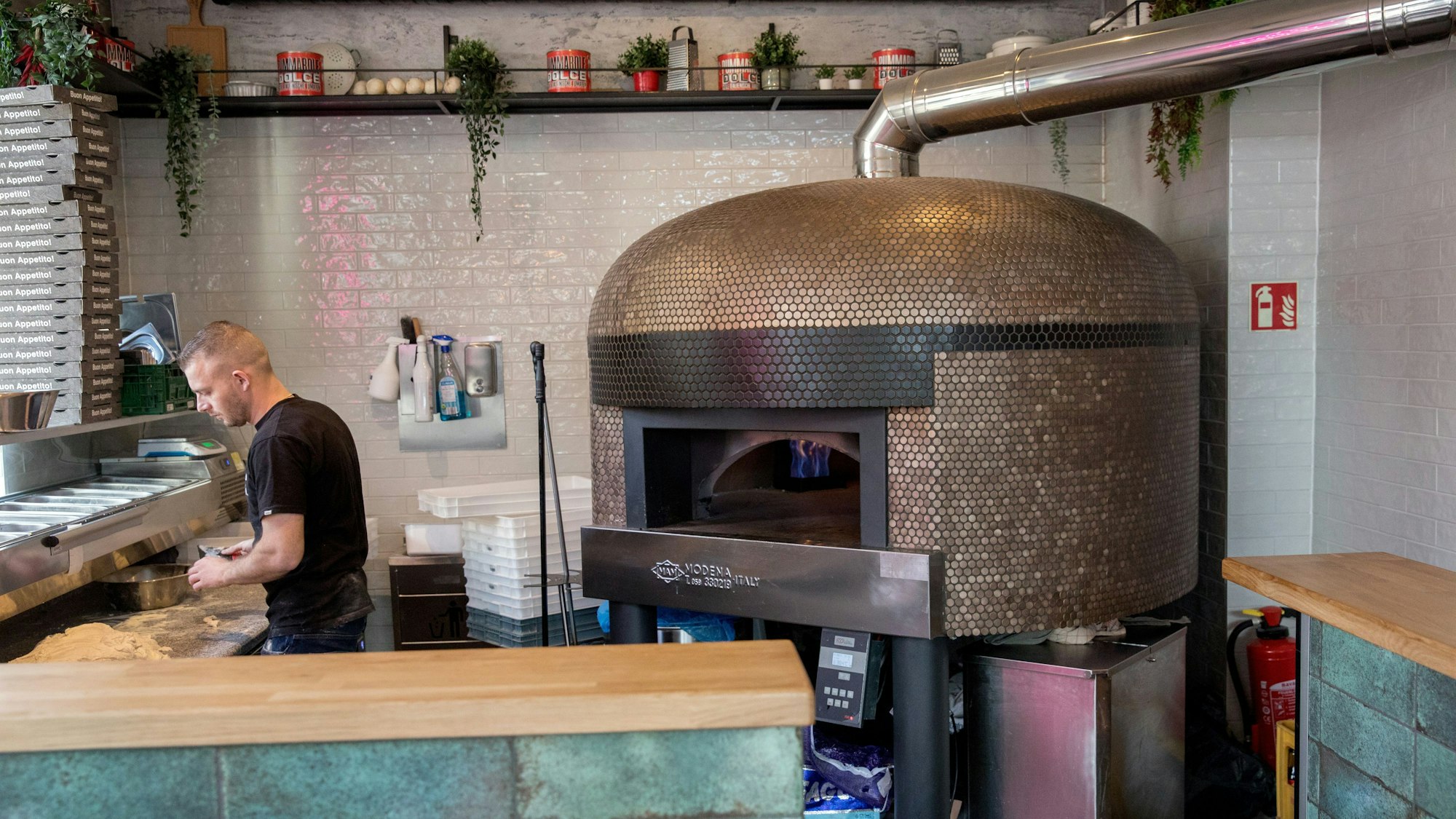 Ein großer Pizzaofen. Drinnen leuchtet eine Flamme.