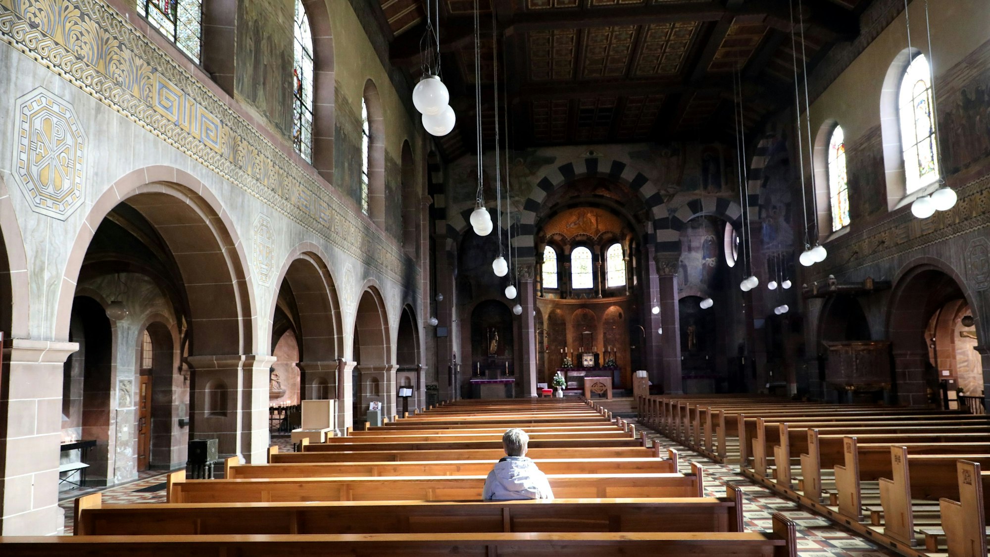Eine Frau sitzt alleine in der Kirche St. Laurentius in Bergisch Gladbach.
