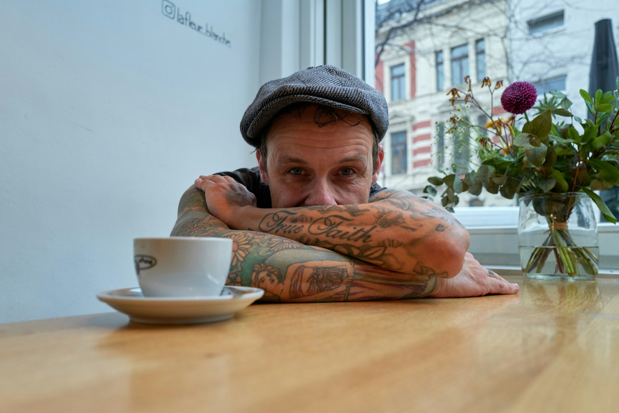 Ingo Knollmann am Tisch im Café in Ehrenfeld mit einer Tasse Kaffee.