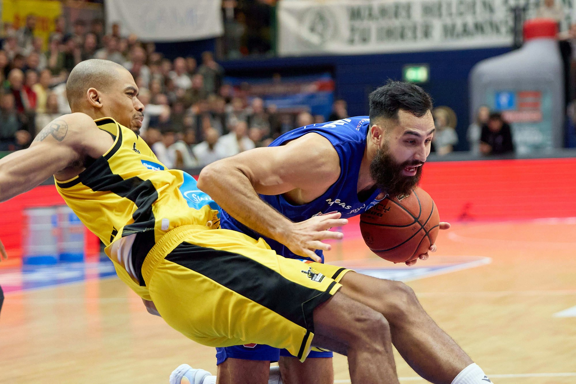 Ein Basketballer stößt auf dem Weg zum Korb seinen Gegenspieler um.