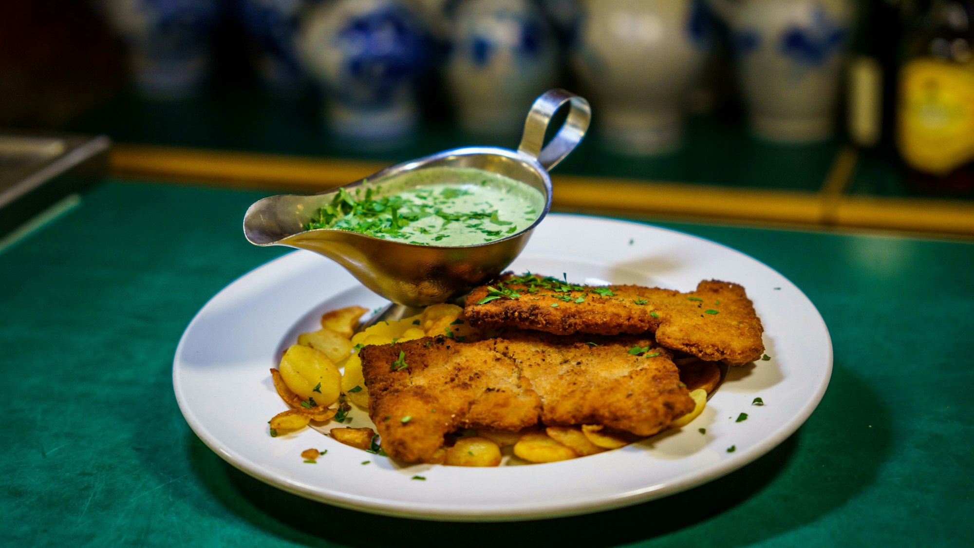 Ein veganes "Frankfurter Schnitzel" mit veganer "Grüner Soße" steht auf der Theke.