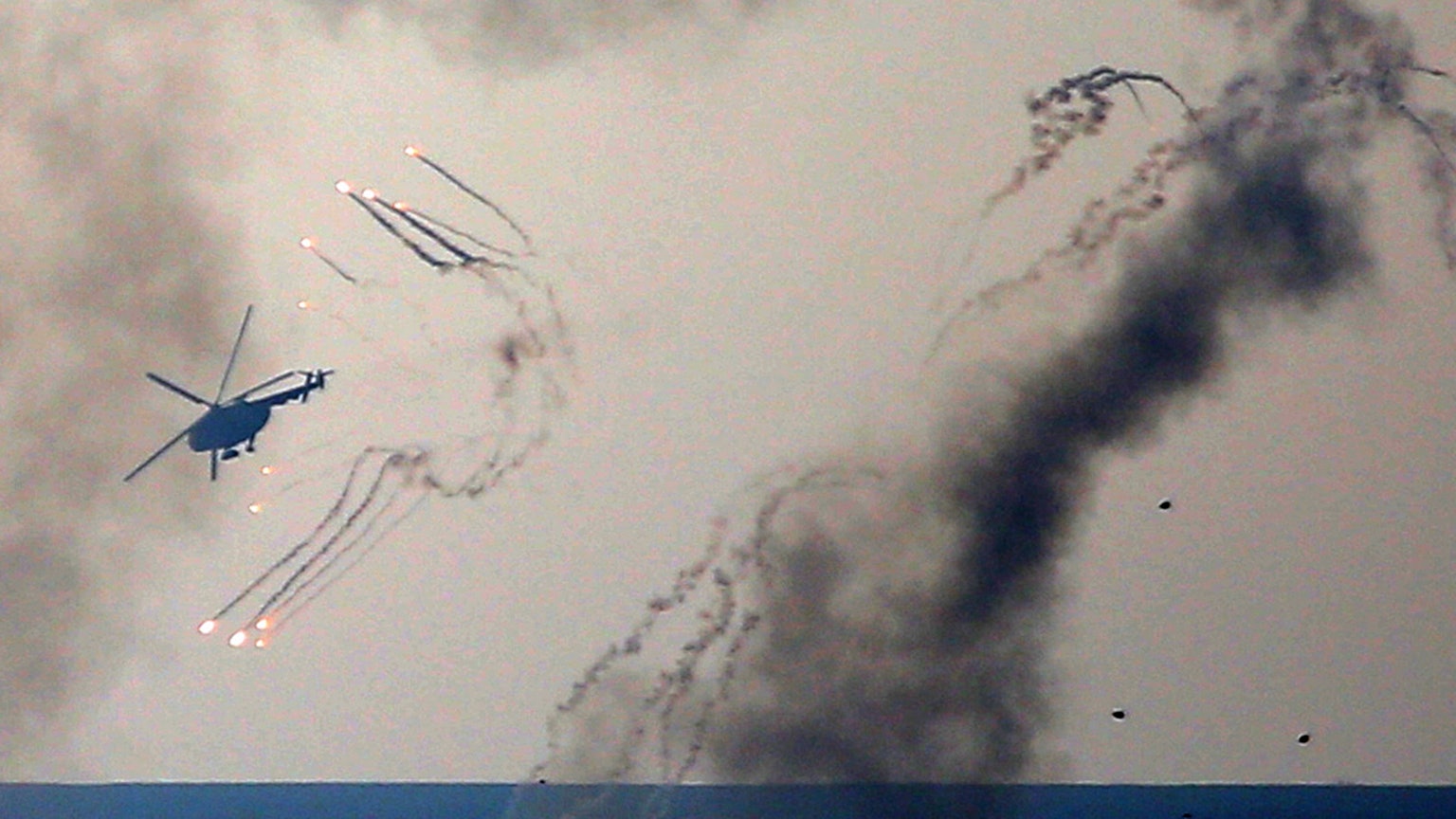 Ein ukrainischer Helikopter feuert Abwehrgeschütze ab und Rauch steigt auf.