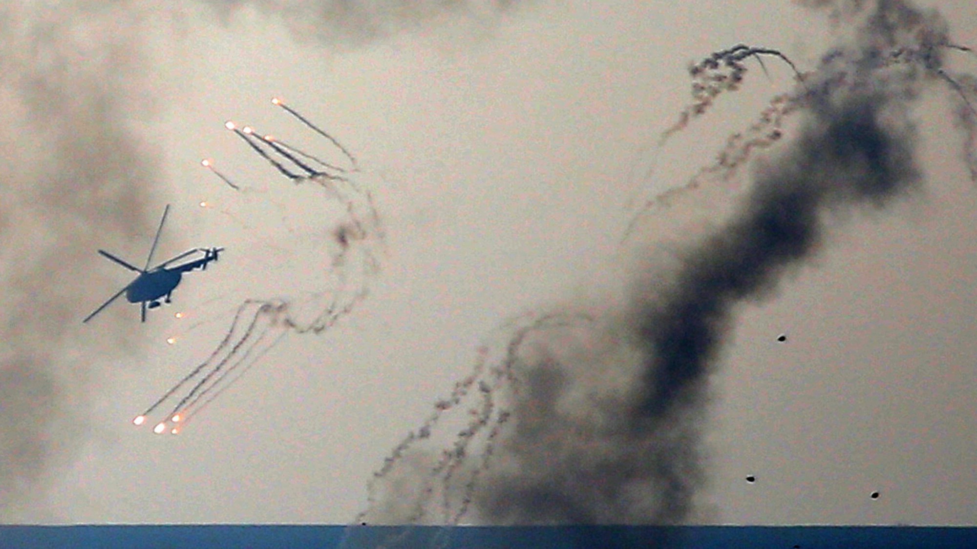 Ein ukrainischer Helikopter feuert Abwehrgeschütze ab und Rauch steigt auf.