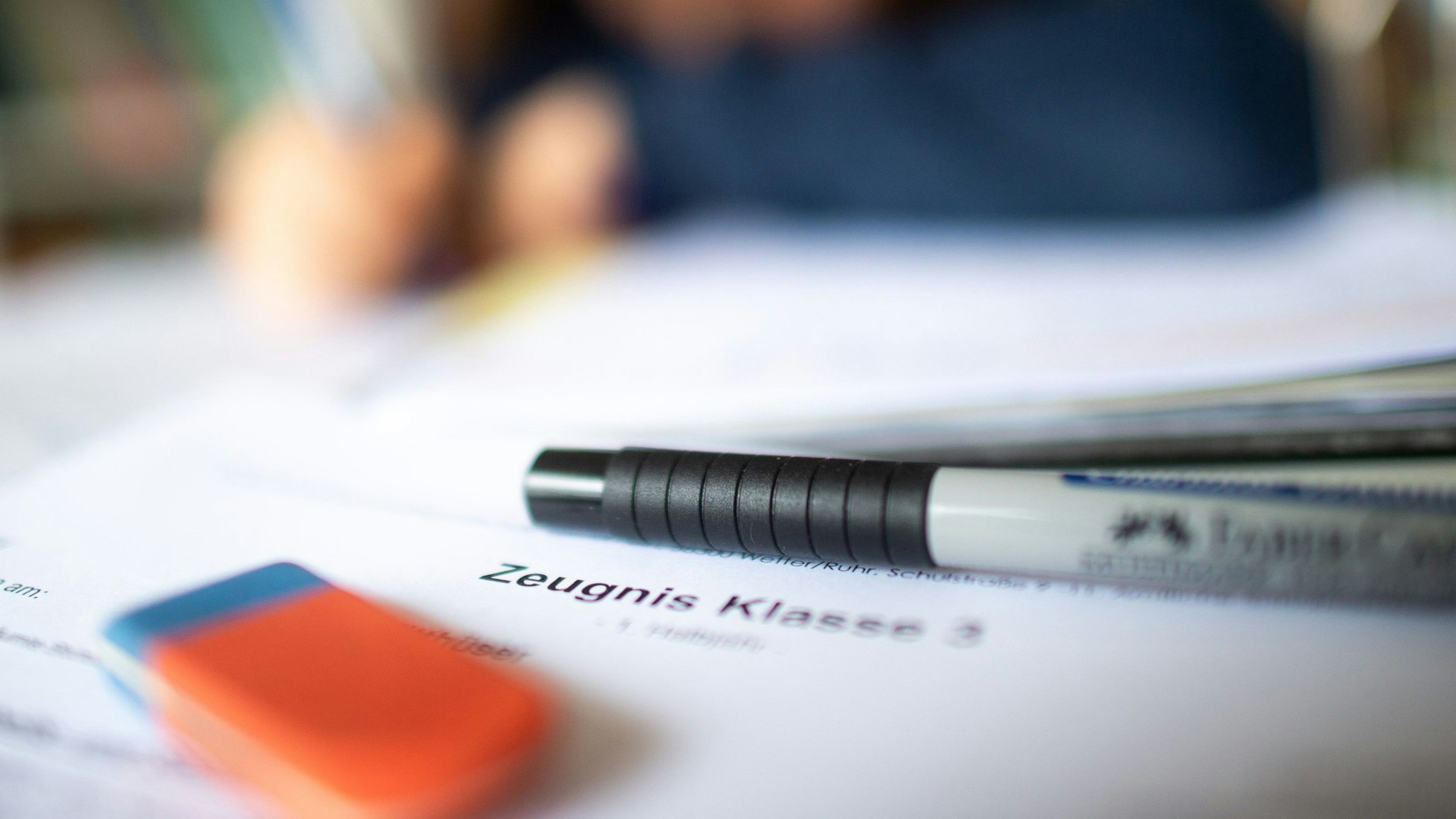 Eine Schülerin der dritten Klasse arbeitet an ihrem Schreibtisch, während ihr Zeugnis auf ihrem Schreibtisch liegt.