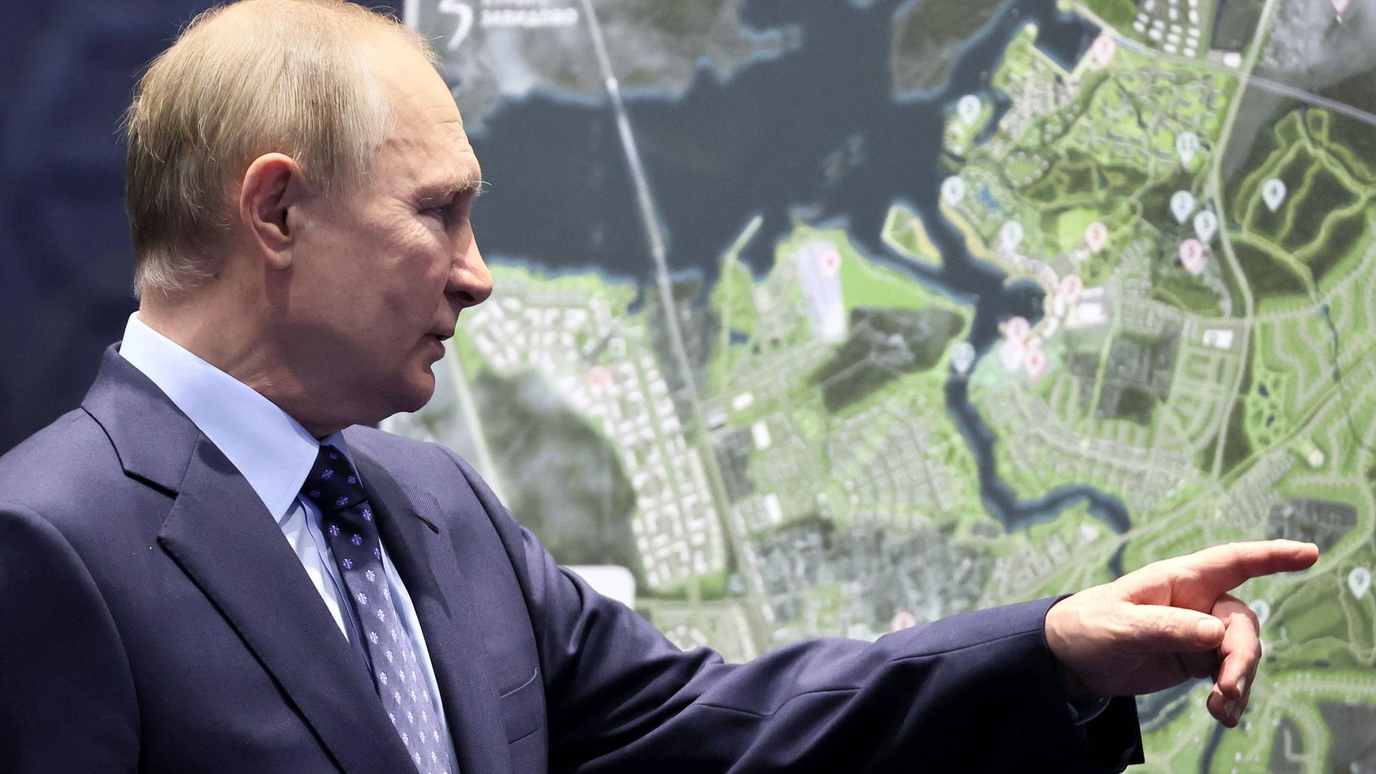 Wladimir Putin zeigt mit dem Finger auf eine Landkarte.