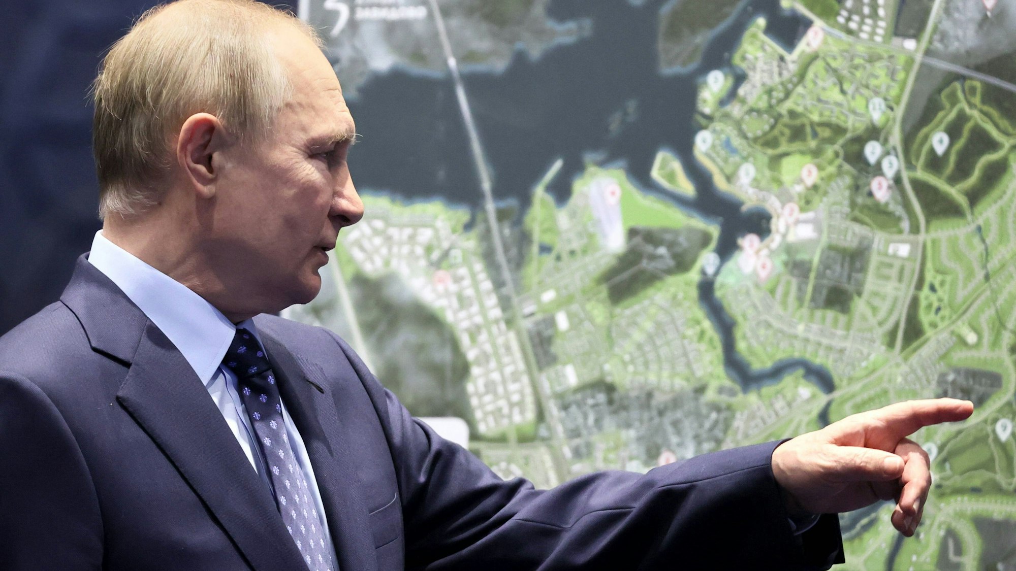 Wladimir Putin zeigt mit dem Finger auf eine Landkarte.