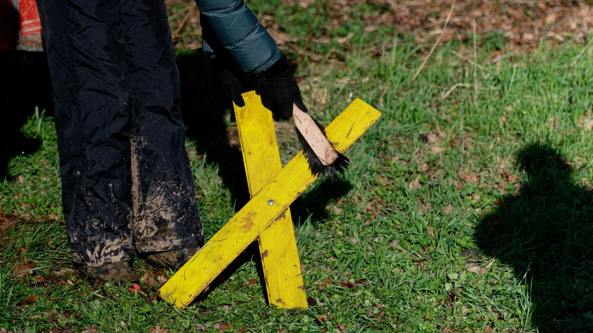 Eine Aktivistin reinigt in Lützerath in Keyenberg ein Gelbes Kreuz.