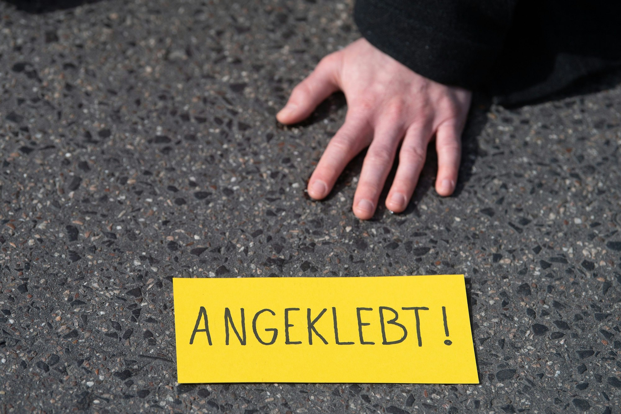 Ein Demonstrant hat sich während eines Protests der Gruppe Letzte Generation auf einer Straße festgeklebt.