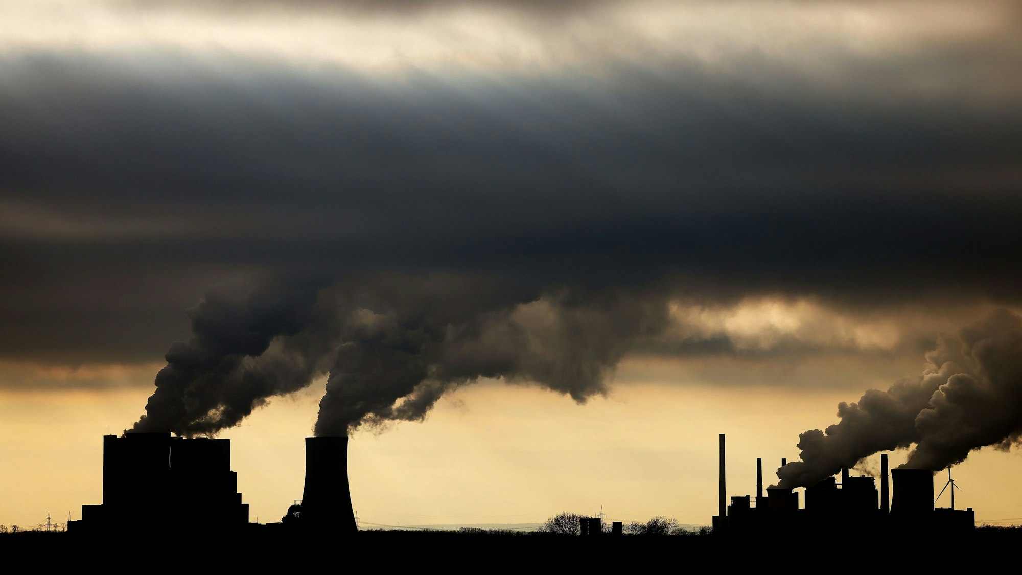 Dampf und Rauch steigt im Gegenlicht aus den Braunkohlekraftwerken Neurath II (l) und Neurath I bei Grevenbroich auf.