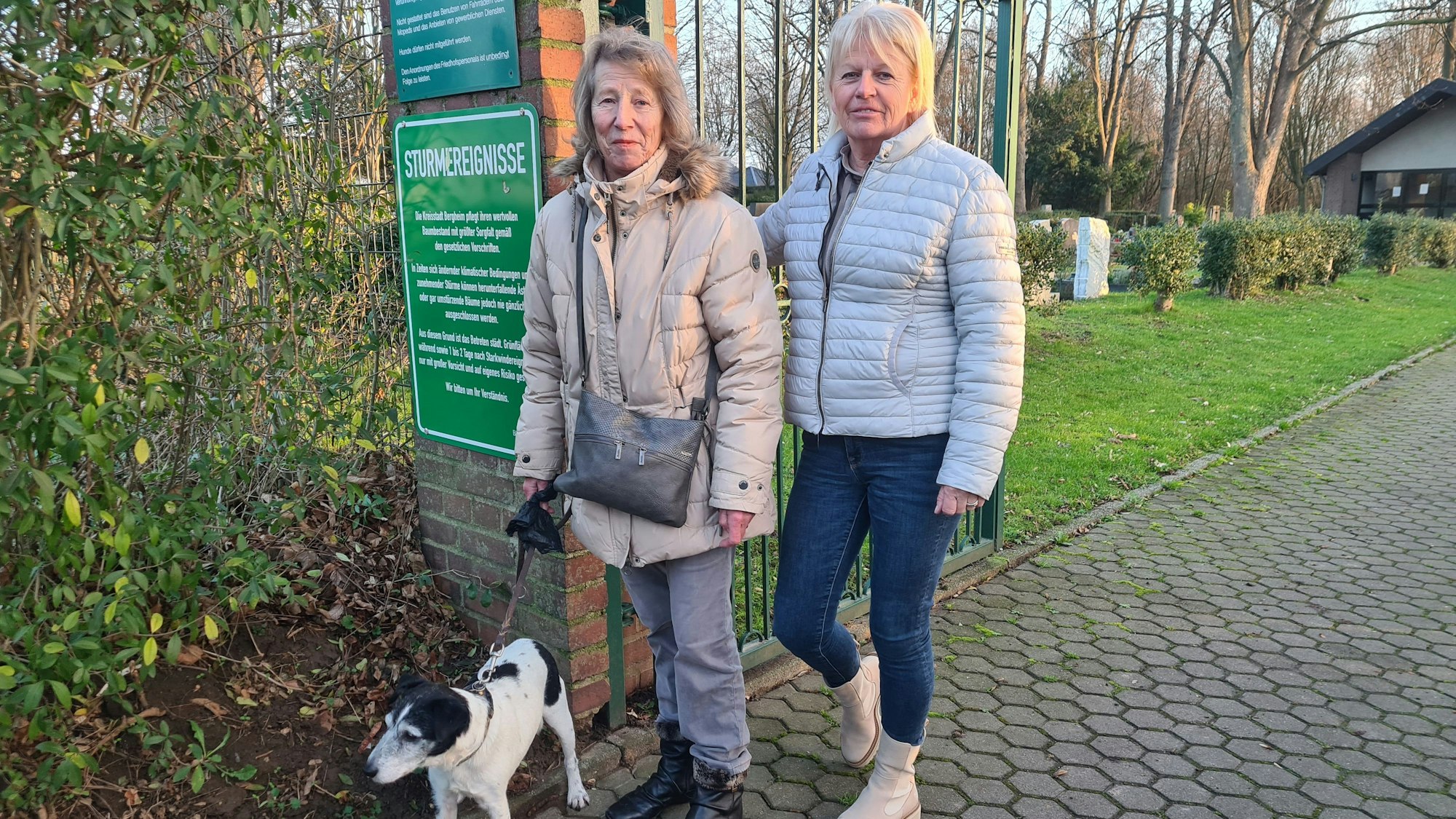 Marianne Mödder steht mit ihrem Hund vor dem Friedhof in Fliesteden.