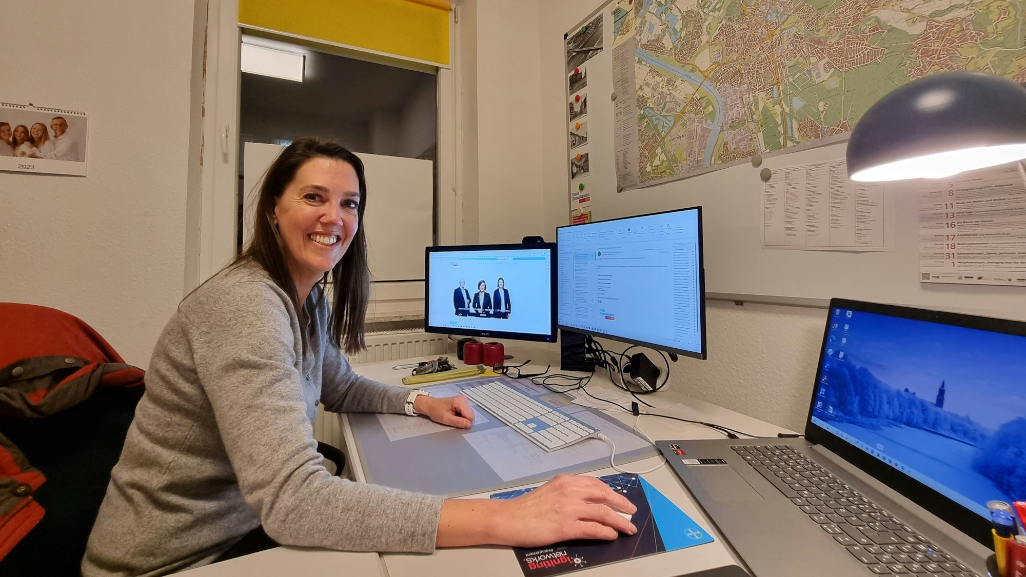 Valeska Hansen sitzt an einem Schreibtisch vor zwei Computerbildschirmen und hat den Kopf zur Kamera gedreht.