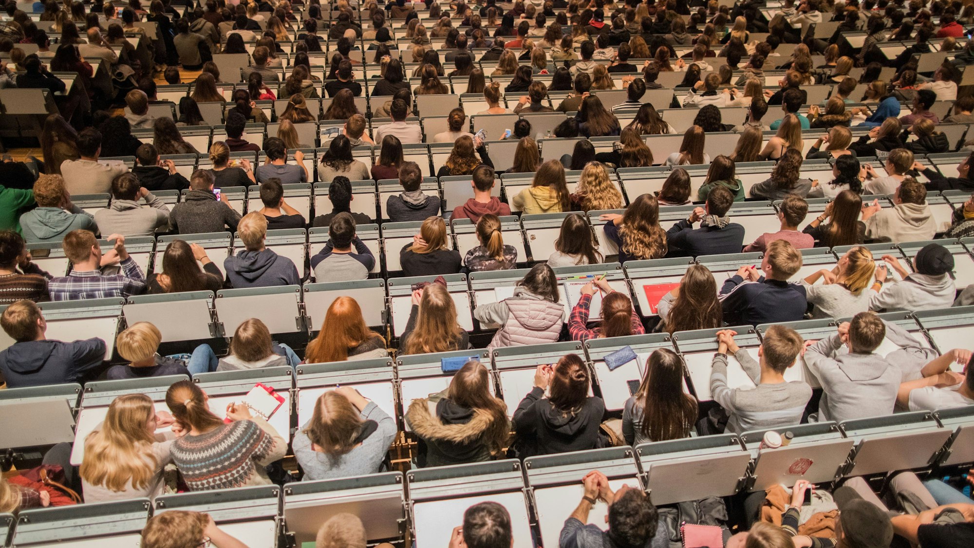 Studenten verfolgen im Hörsaal im Hauptgebäude der Universität zu Köln die Erstsemesterbegrüßung.