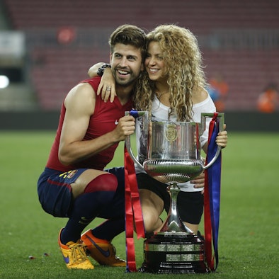 Gerard Pique posiert mit seiner Frau Shakira vor einem Pokal.