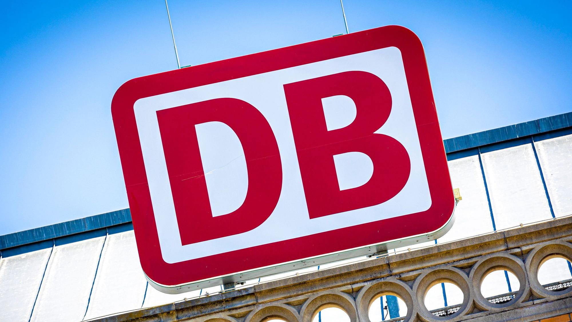 Das Logo der Deutschen Bahn über einem Hauptbahnhof.