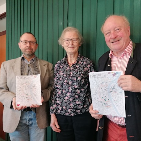 Alexander Hess, Henriette Meynen und Konrad Adenauer mit dem Magazin in der Hand vor einer grünen Wand.