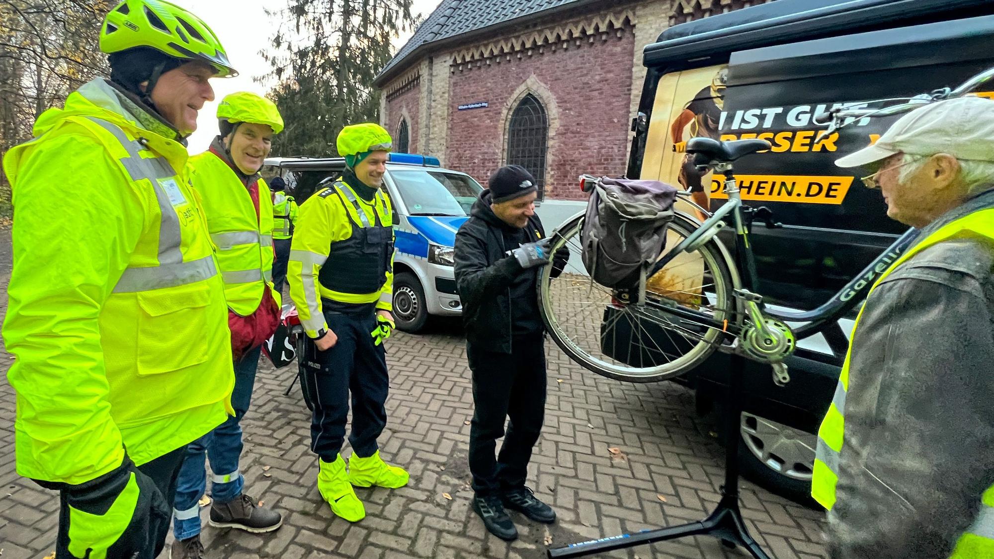 Kurt Krefft und Rolf Awater vom ADFC stehen mit Mario Weidgang von der Polizei und Andreas Kaurisch vom ADAC in leuchtender Kleidung vor einem Fahrrad