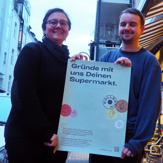 Miriam Schifferman und Malte Garrecht halten ein Werbeplakat in der Hand.