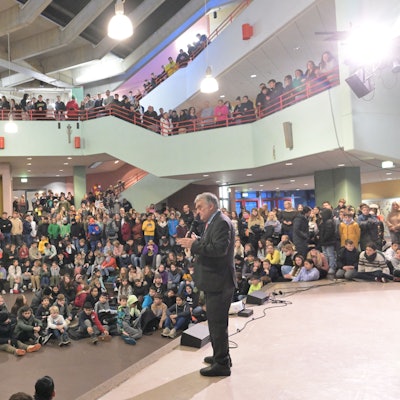 Innenminister Herbert Reul steht auf einer Bühne und spricht zu Schülerinnen und Schüler.