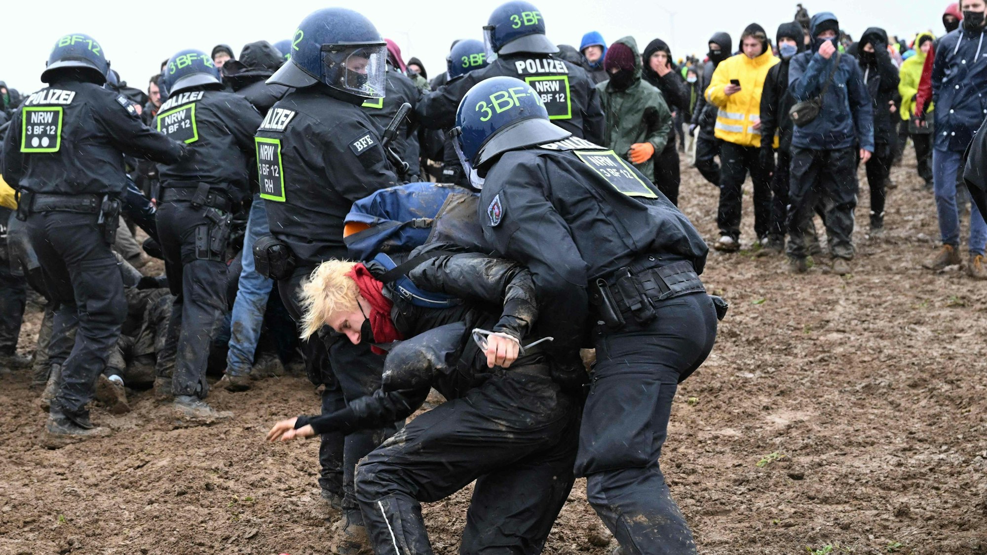 Zwei Polizisten ziehen einen Demonstranten während der Proteste gegen den Abriss von Lützerath weg.