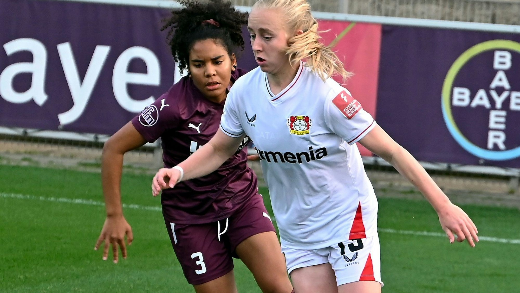 Zwei Fußballerinnen befinden sich im Zweikampf.