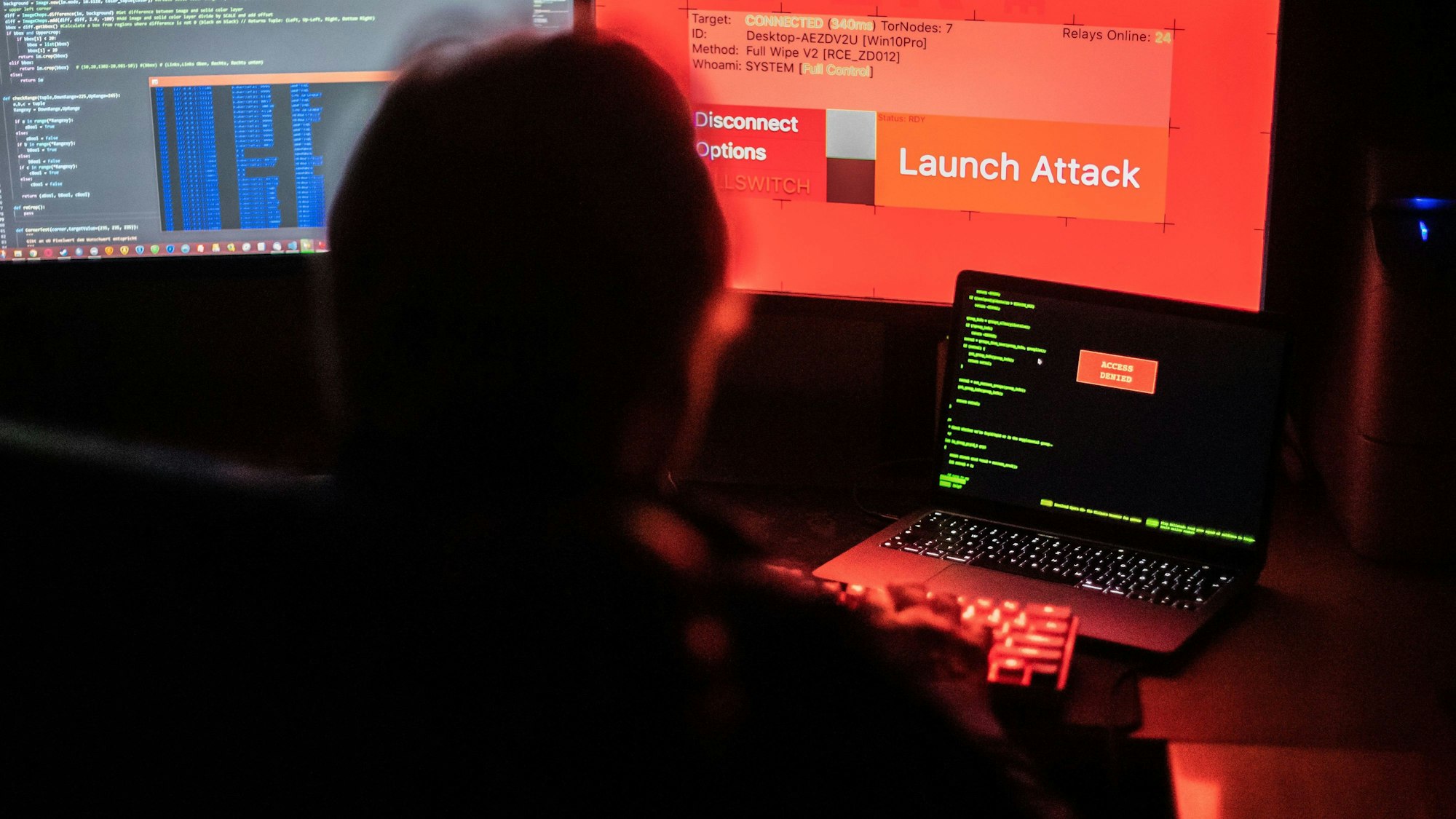 Ein Mann sitzt vor Bildschirmen, die Hacker-Programme und eine fiktive Fernlösch-Software zeigen (Archivbild).