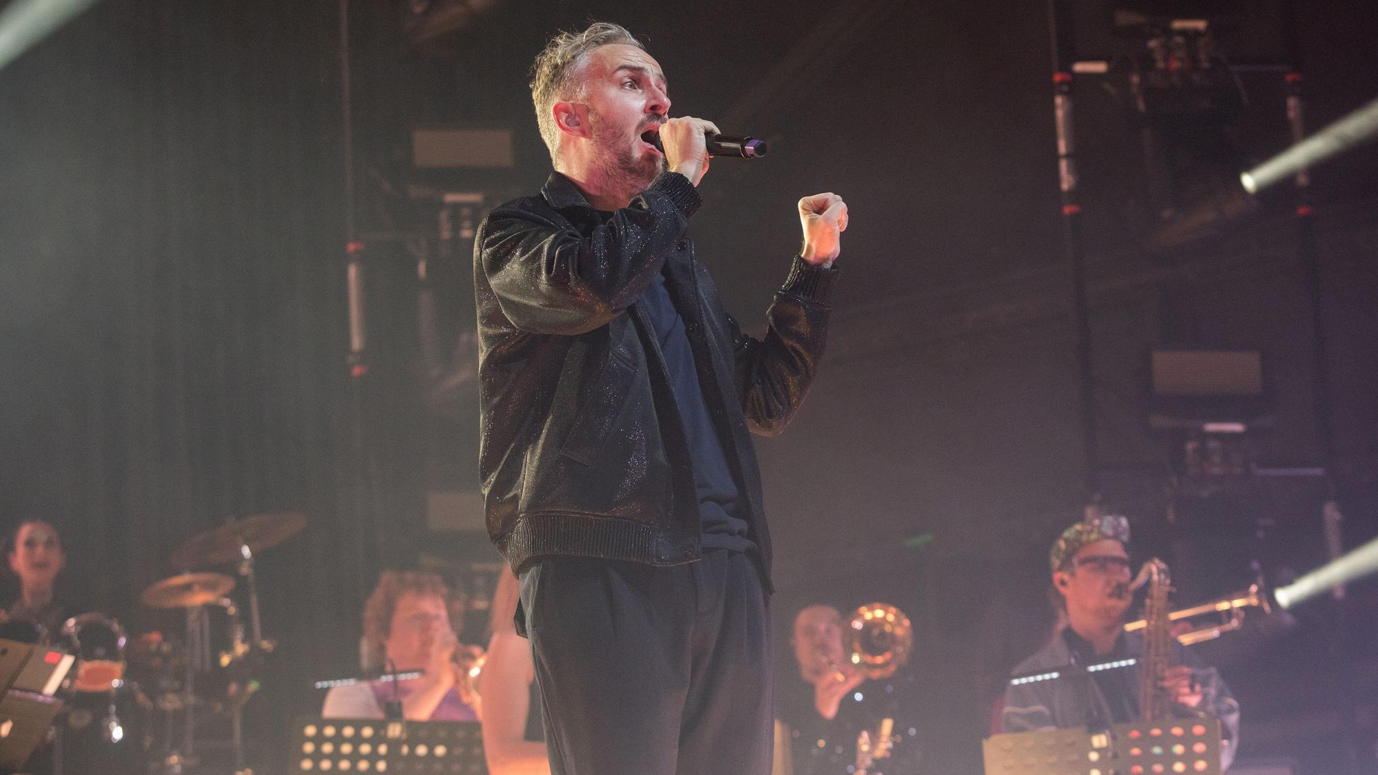 Jan Böhmermann steht singnd vor dem Rundfunktanz-Orchester Ehrenfeld auf der Bühne des Palladium in Köln-Mülheim.