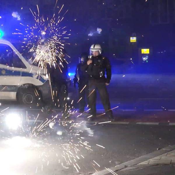 Berliner Polizeibeamte stehen in der Silvesternacht 2022/203 hinter explodierendem Feuerwerk.