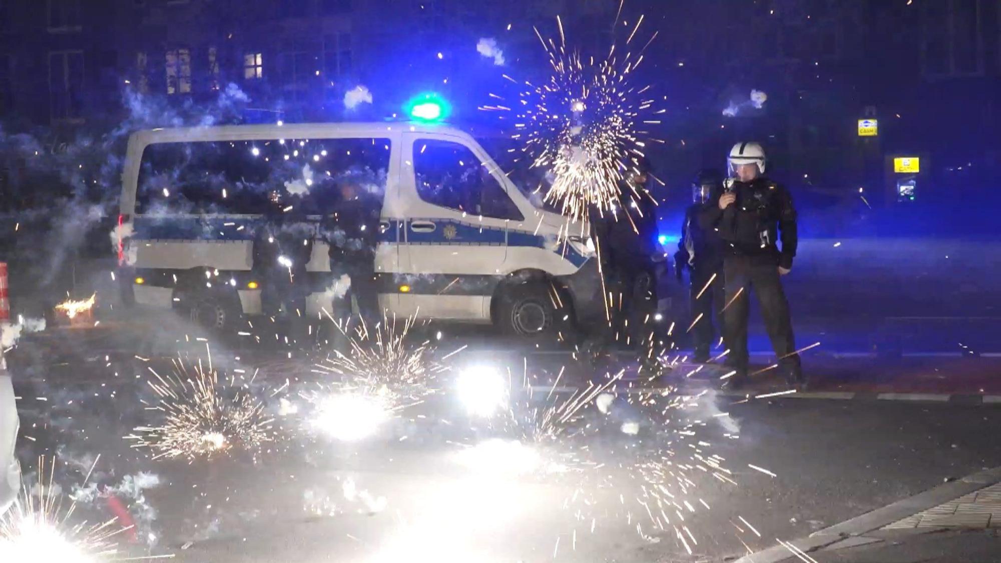 Berliner Polizeibeamte stehen in der Silvesternacht 2022/203 hinter explodierendem Feuerwerk.
