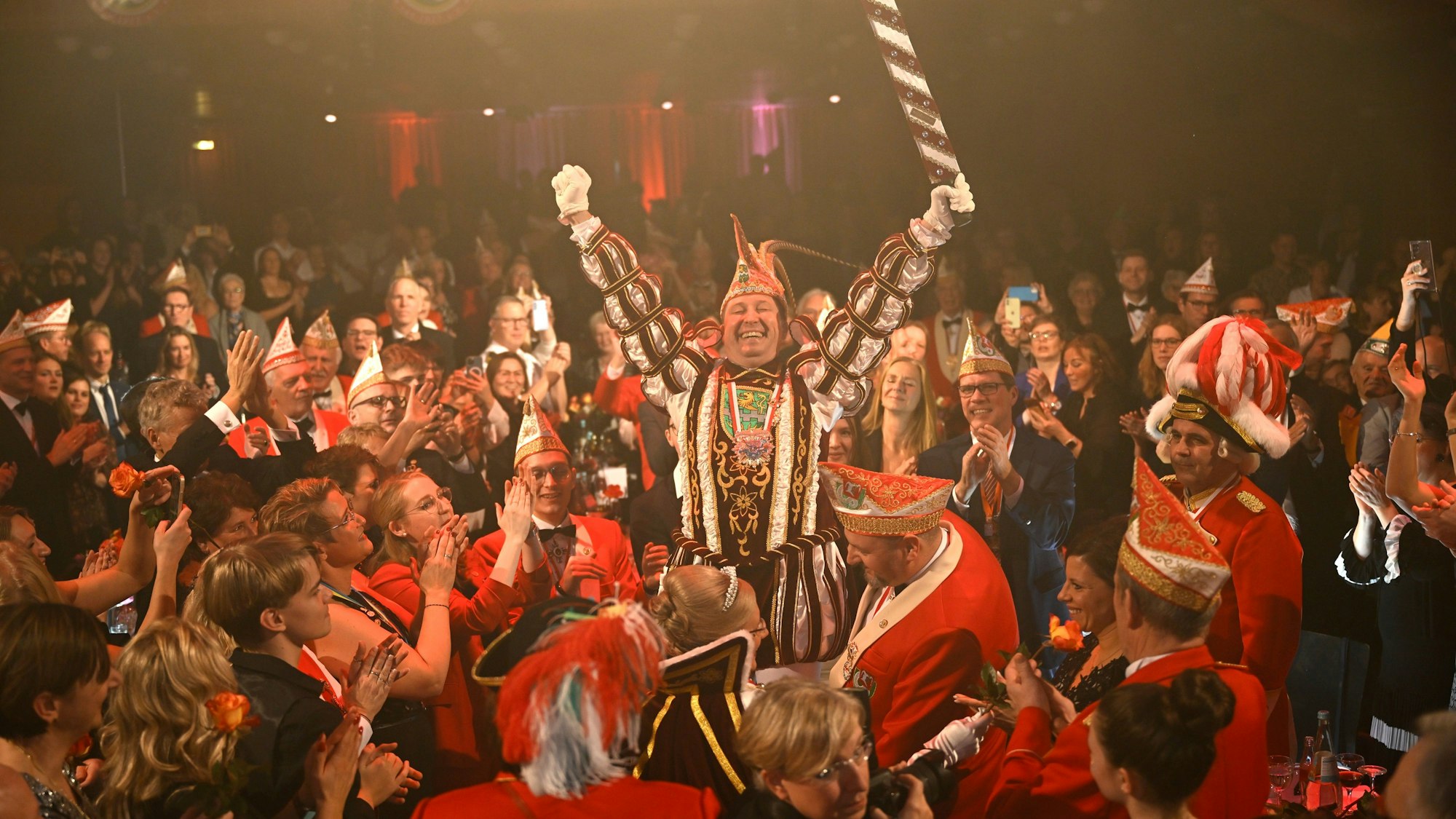 Frank Haag steht im Prinzenornat auf einem Stuhl im jecken Publikum.
