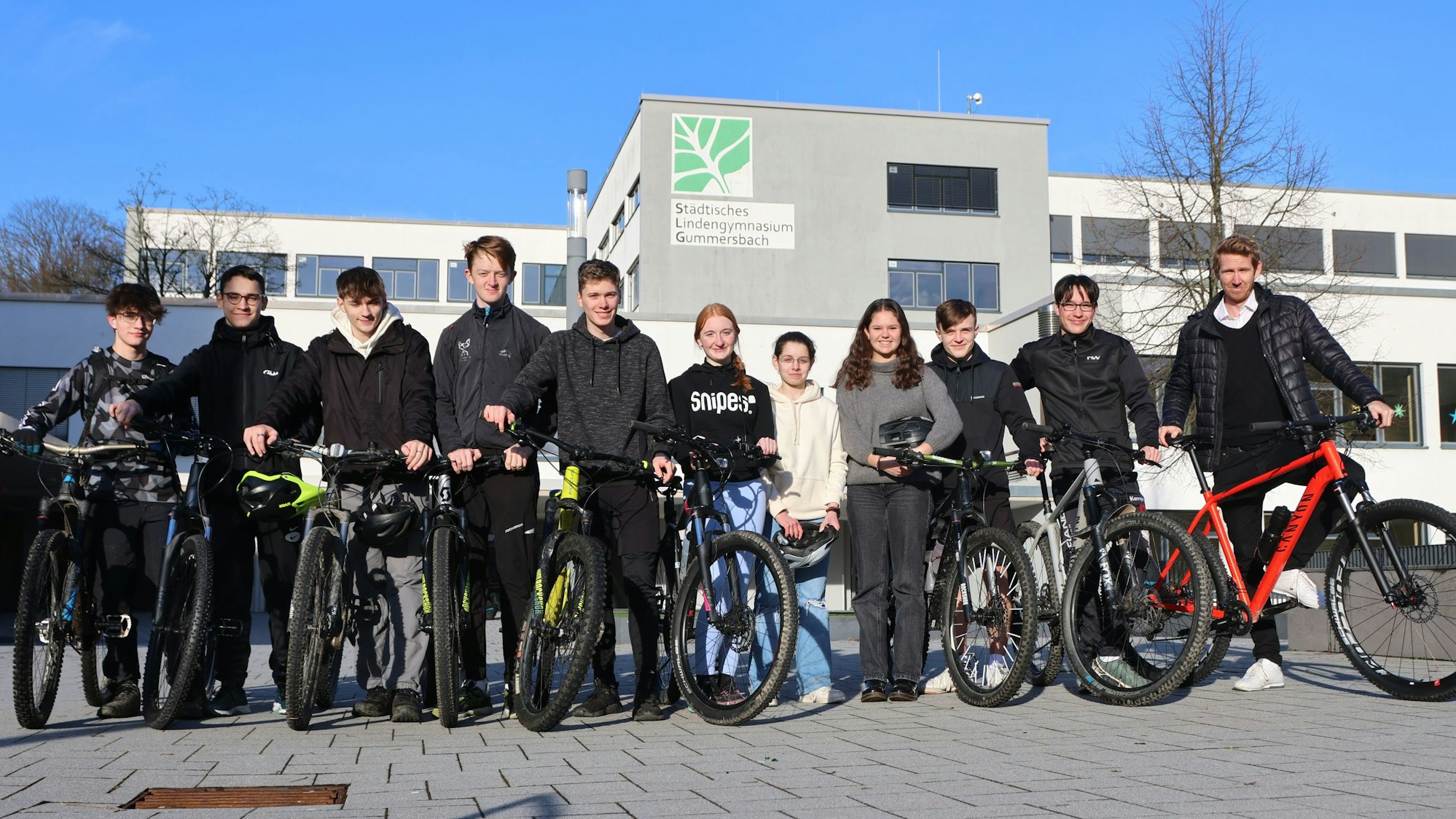 Mehrere Jugendliche stehen mit ihren Mountainbikes in einer Reihe.