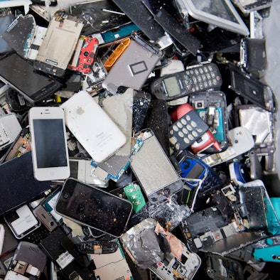 Alte Handys und Smartphones liegen in einem Container, ehe sie geschreddert werden.