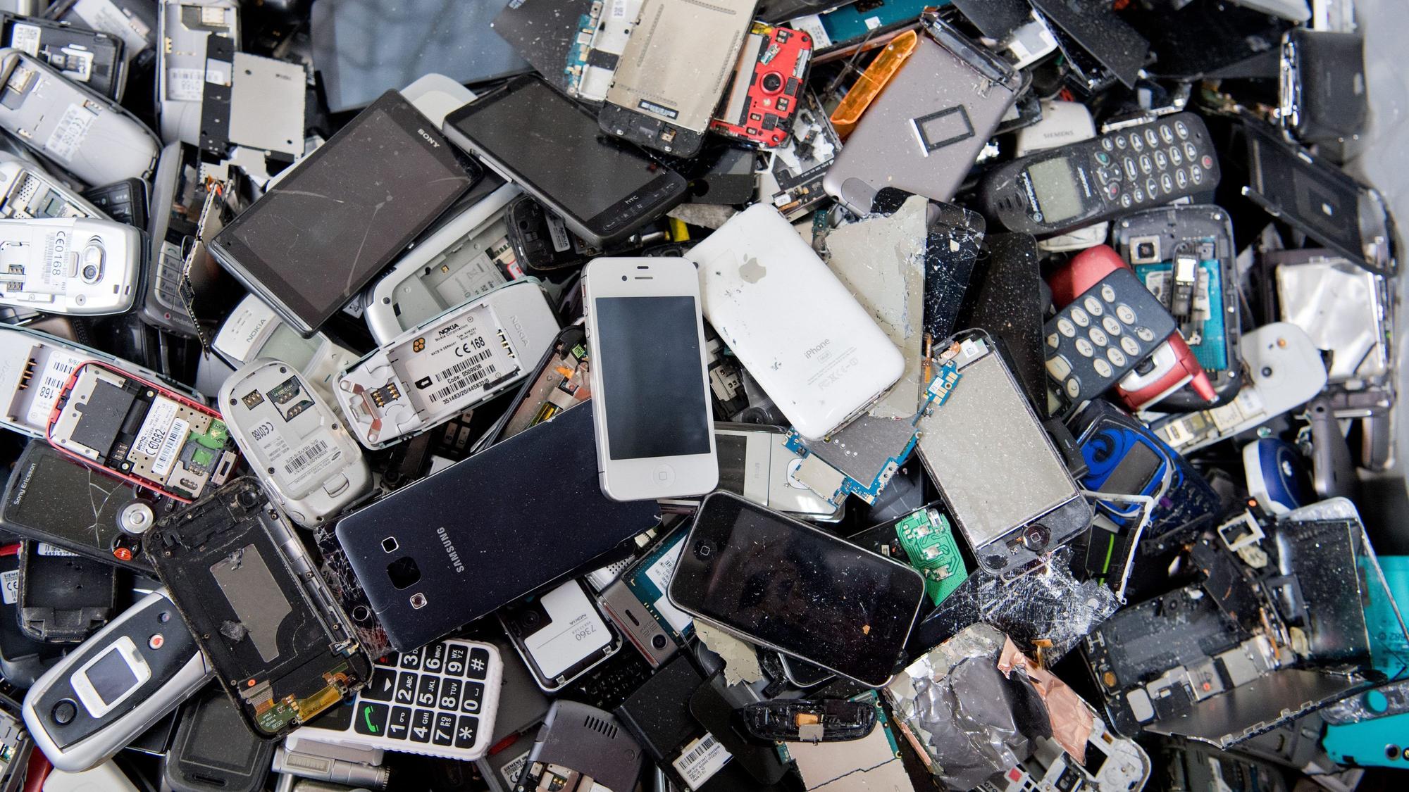 Alte Handys und Smartphones liegen in einem Container, ehe sie geschreddert werden.