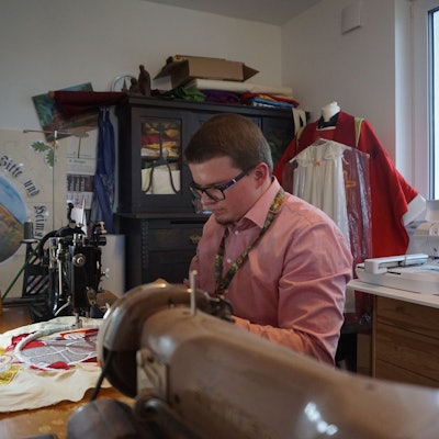 Ein Mann sitzt an einer Nähmschine.