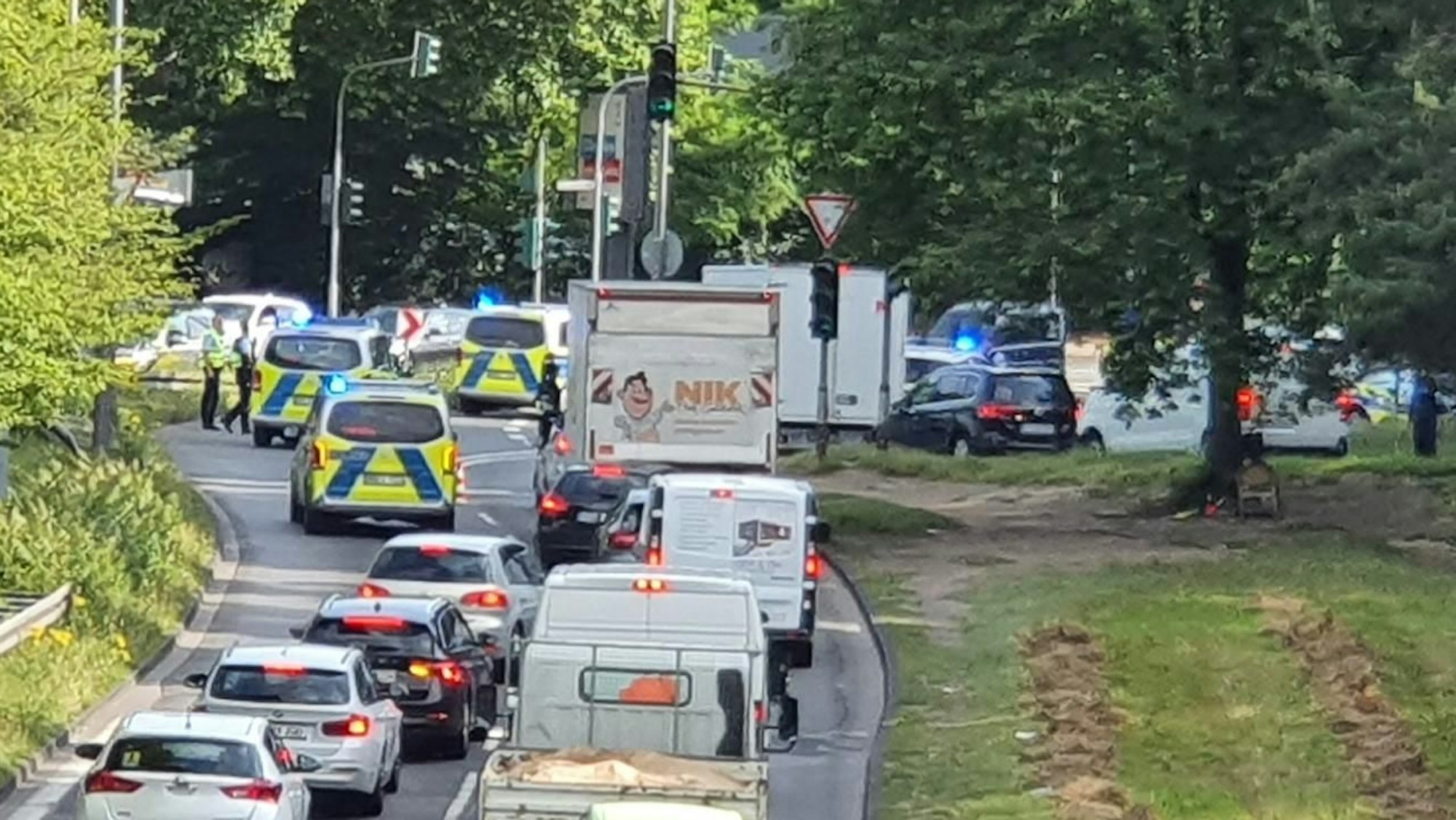 An einer Kreuzung stehen mehrere Polizeifahrzeuge mit angeschaltetem Blaulicht. Dahinter staut sich der Verkehr.