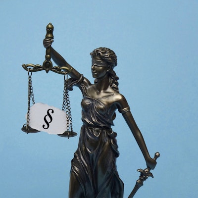 Das Modell der Justitia trägt ein Paragrafensymbol.