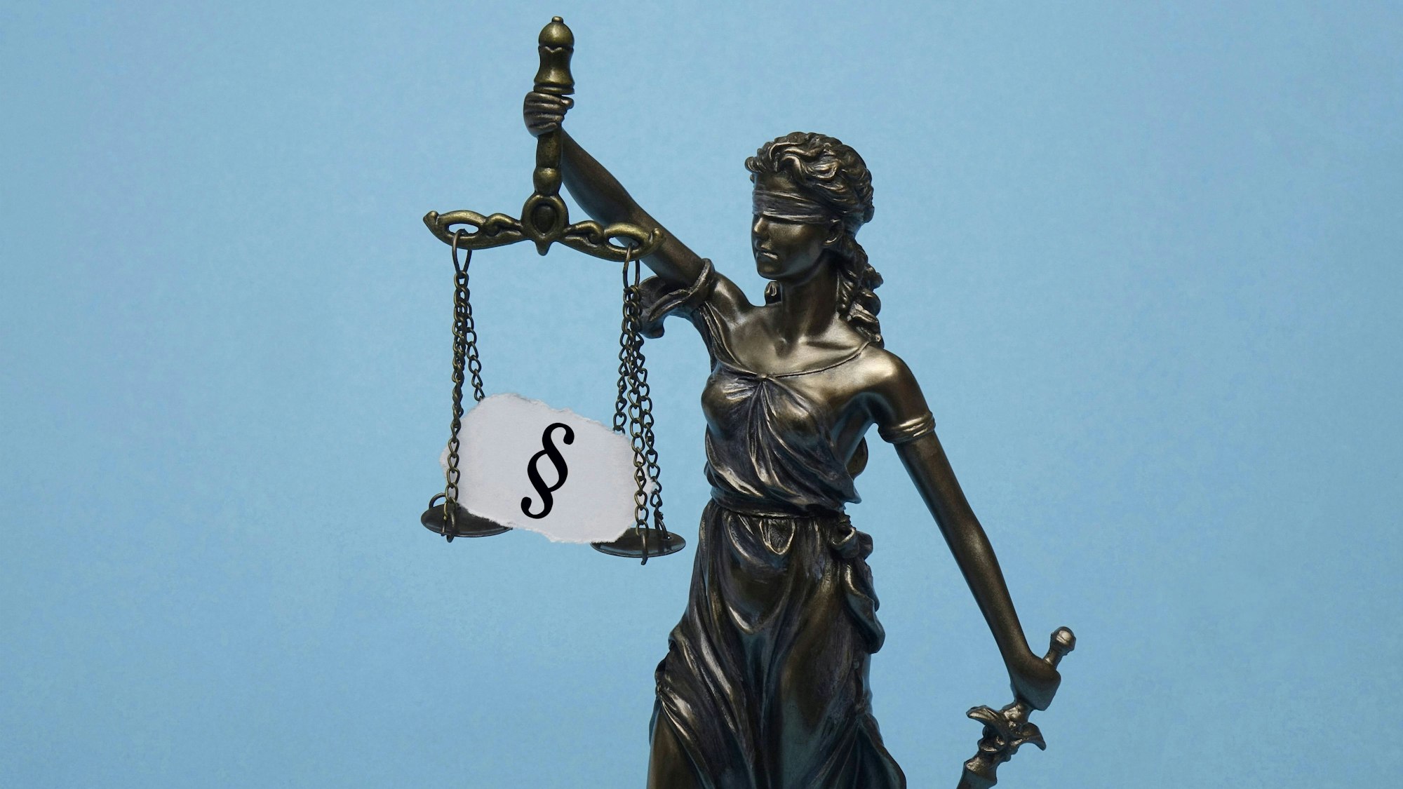 Das Modell der Justitia trägt ein Paragrafensymbol.