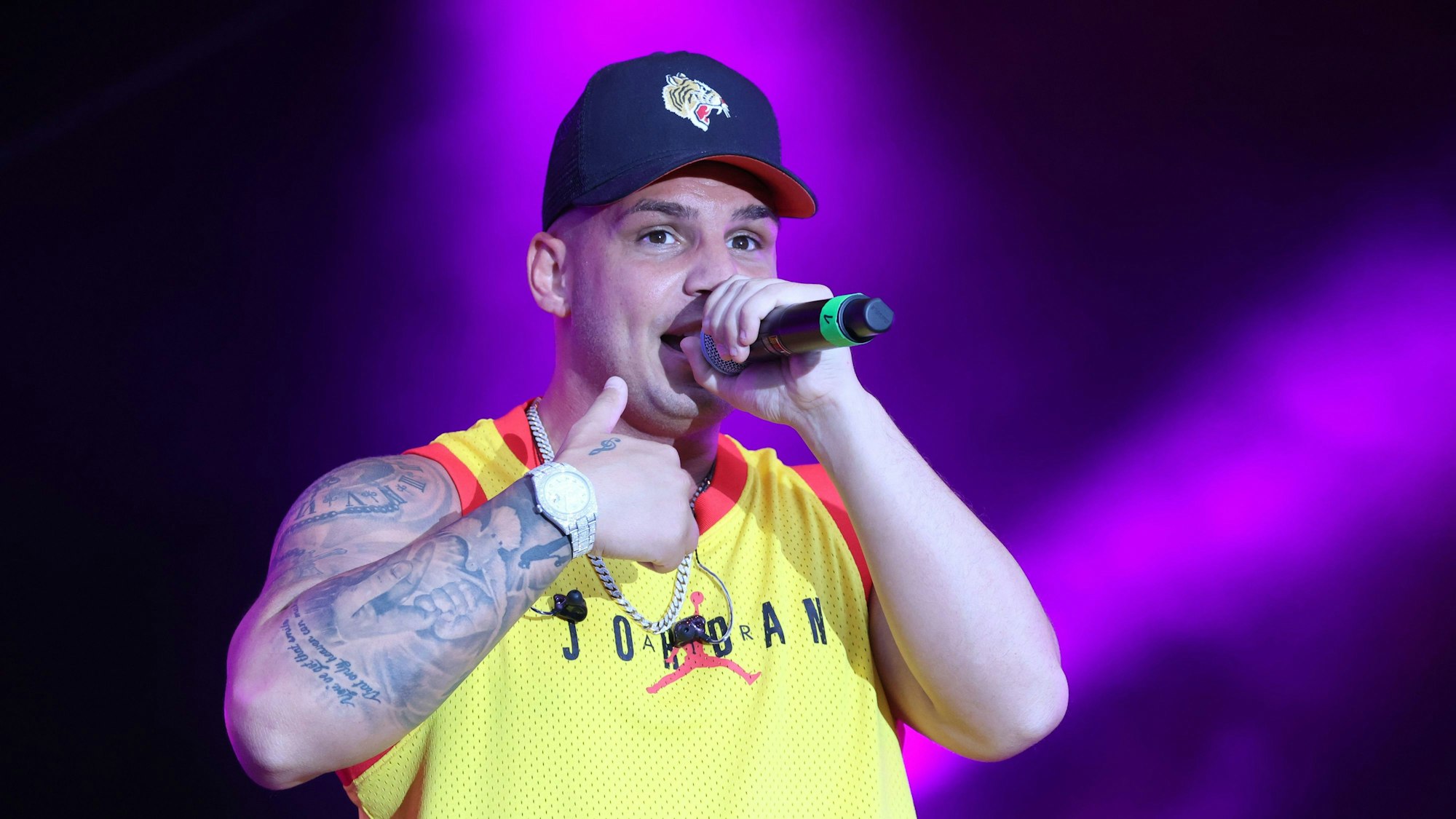 Es ist Pietro mit einem Mikro auf der Bühne zu sehen.