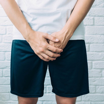 Mann hält sich die Hände vor den Schritt.