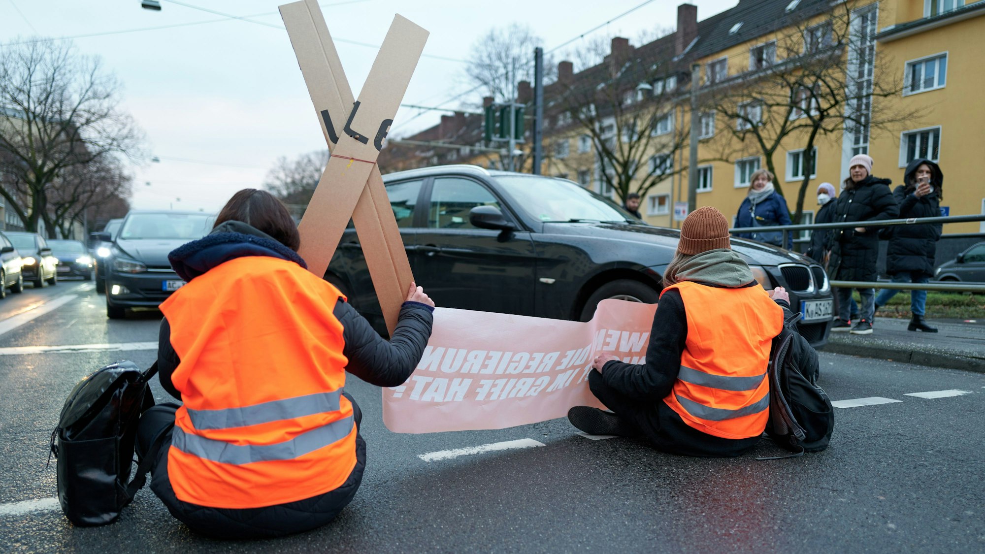 Aktivisten der „Letzten Generation“ kleben sich auf einer Fahrbahn ist Köln fest.