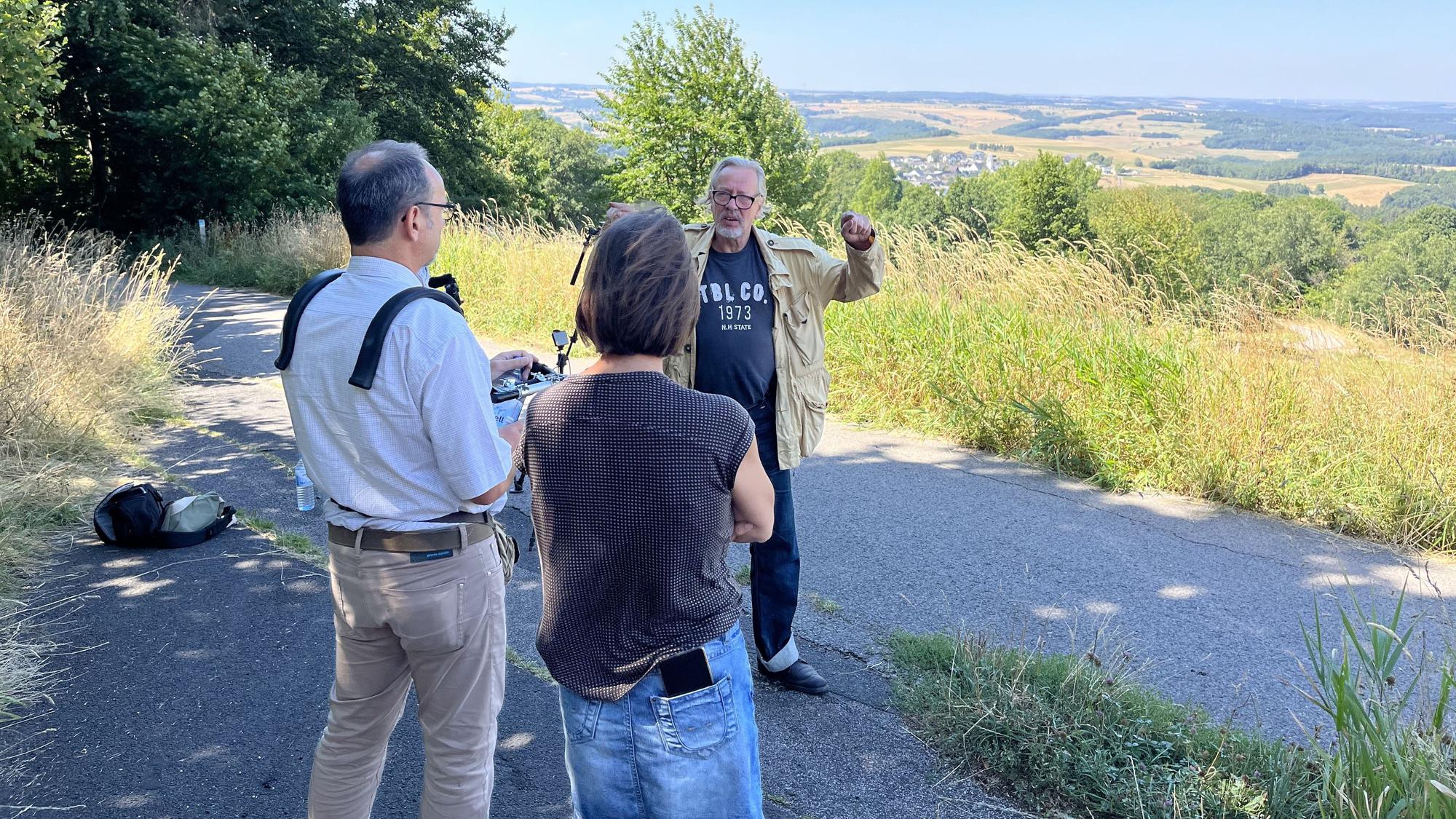 Ein Mann wird gefilmt, im Hintergrund ist Eifeler Landschaft zu sehen.