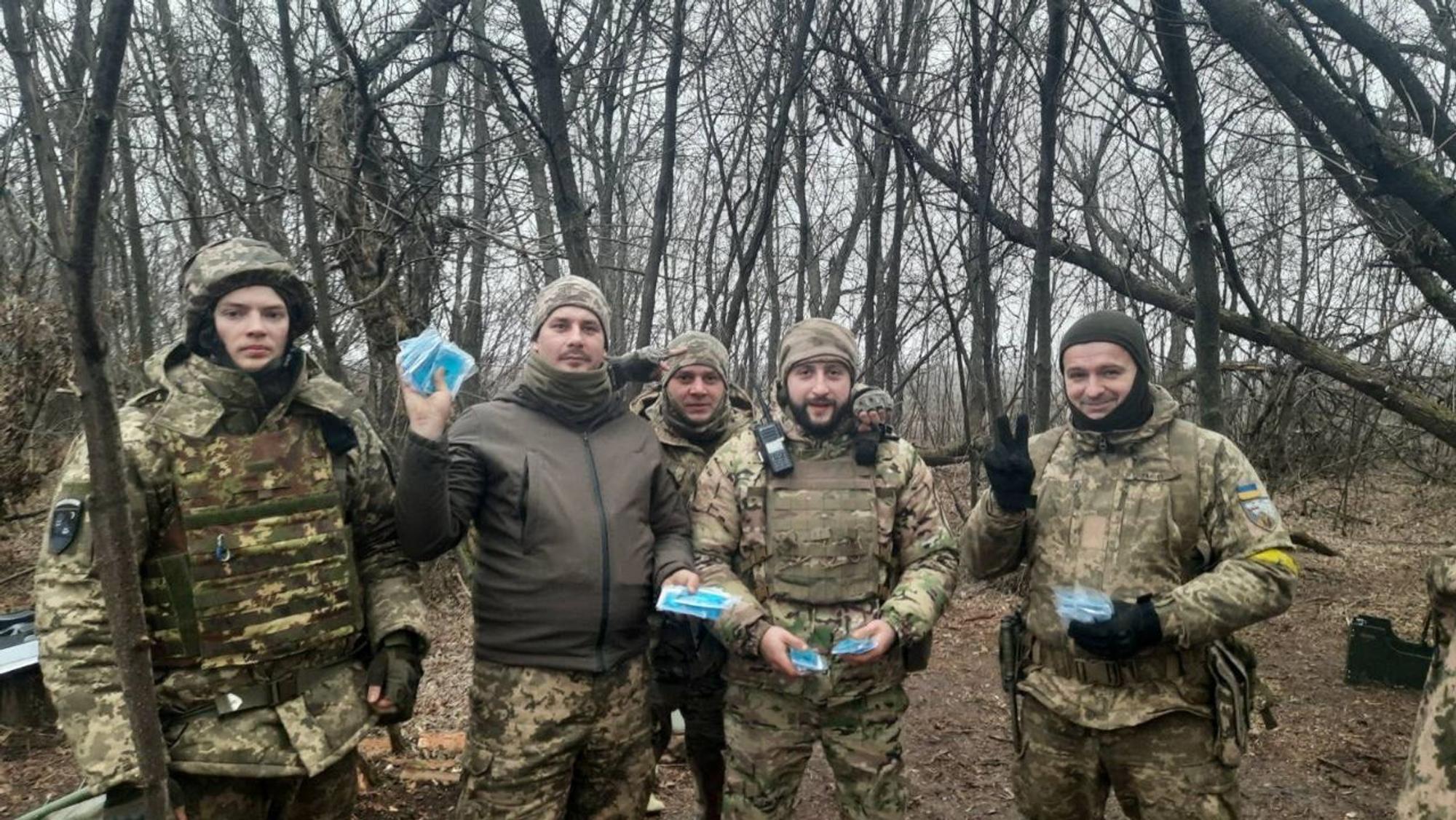 Urkarinische Soldaten halten blaue Handwärmer-Pakete in den Händen.