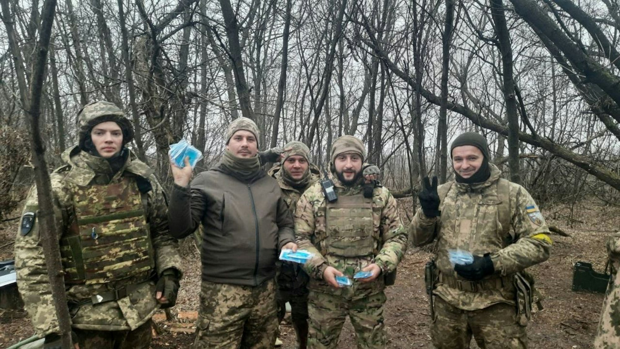 Urkarinische Soldaten halten blaue Handwärmer-Pakete in den Händen.