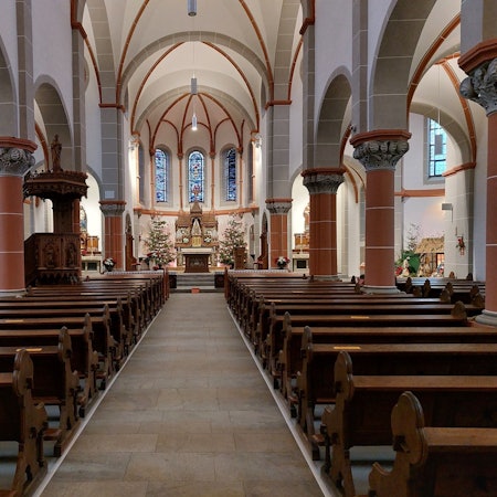 Rechts und links neben einem leeren Gang zum Altar stehen leere Kirchenbänke.